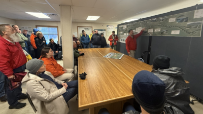 Before heading to the bridge site, Jonathan Tymick of the Alaska DOT briefs meeting attendees on the Juneau Creek Bridge project and surrounding Sterling Highway improvements.